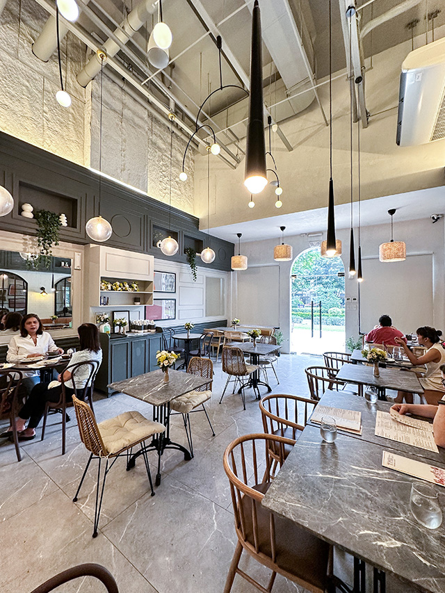 Manila Baker Brew and Bistro — wide interior shot with marble tables and rattan chairs