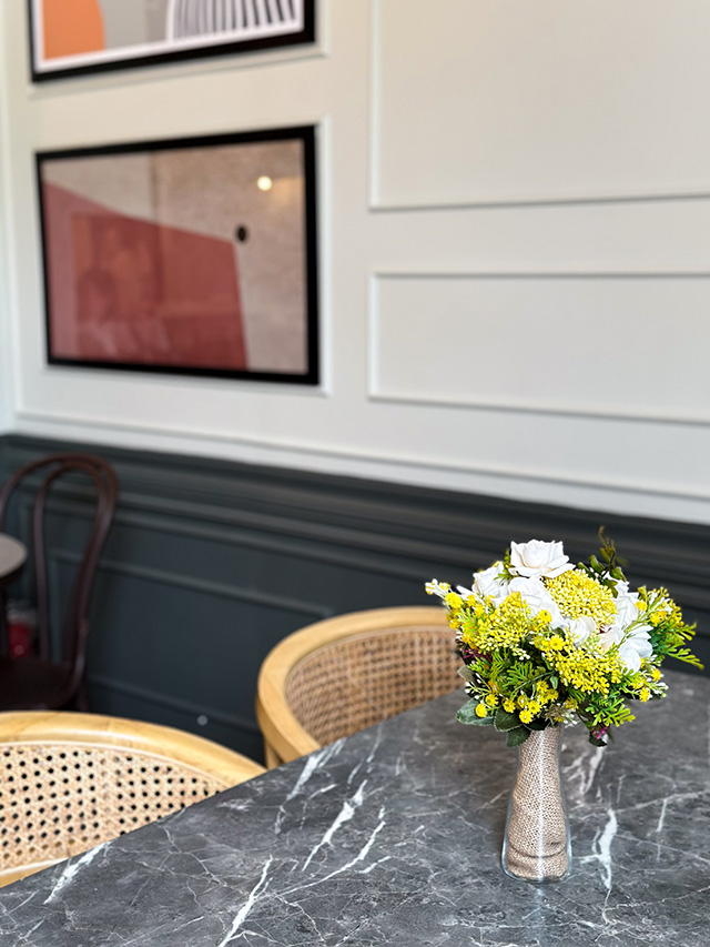 Manila Baker — dark marble table with wall art in warm lighting